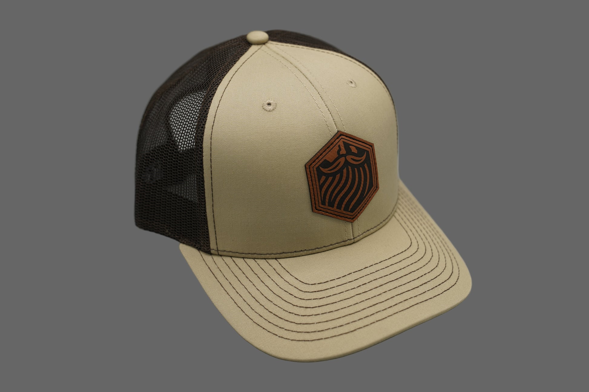 Beige and brown cap with a logo on a gray background