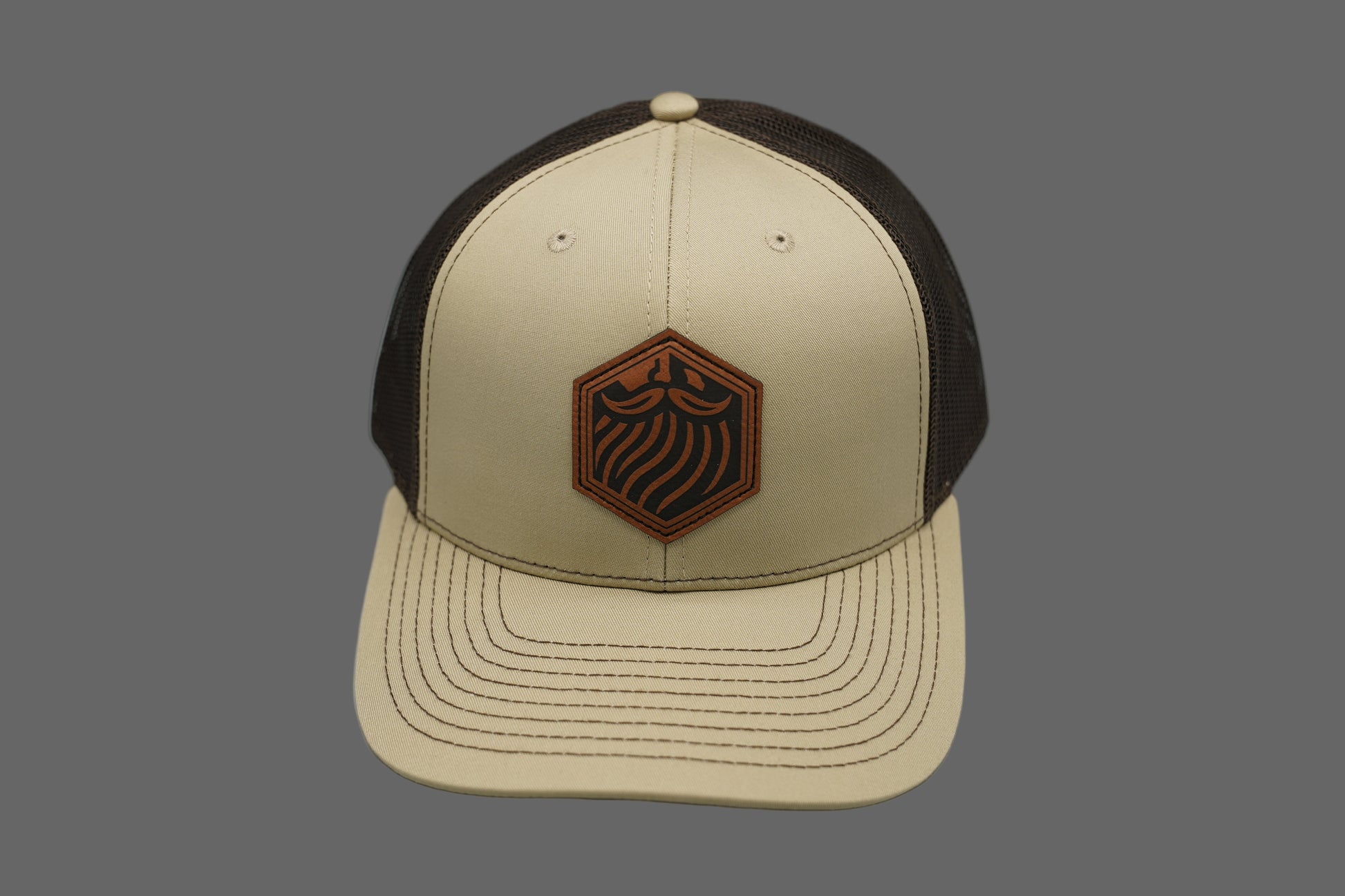 Beige and brown cap with a logo on a gray background