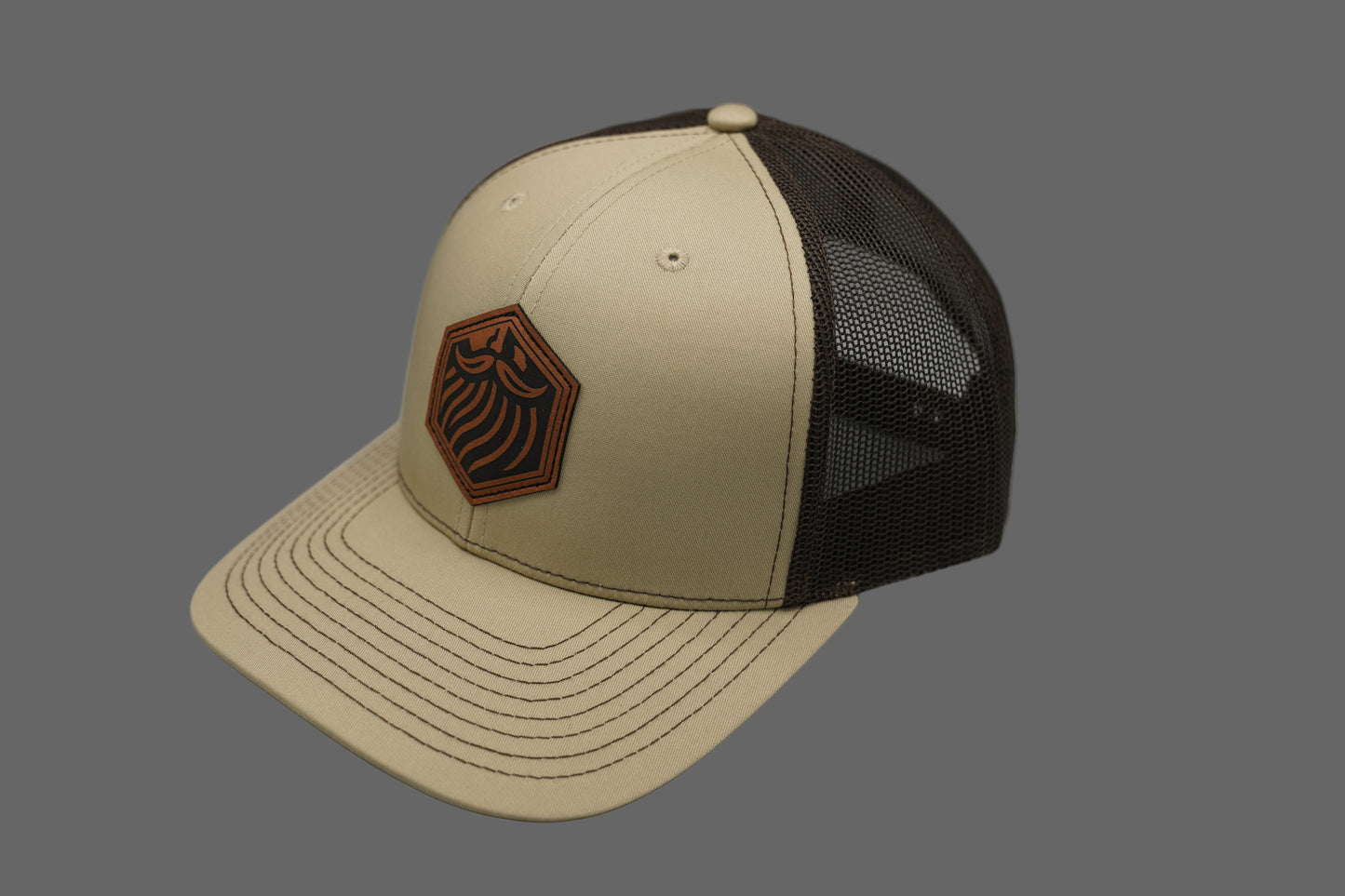 Beige and brown cap with a logo on a gray background