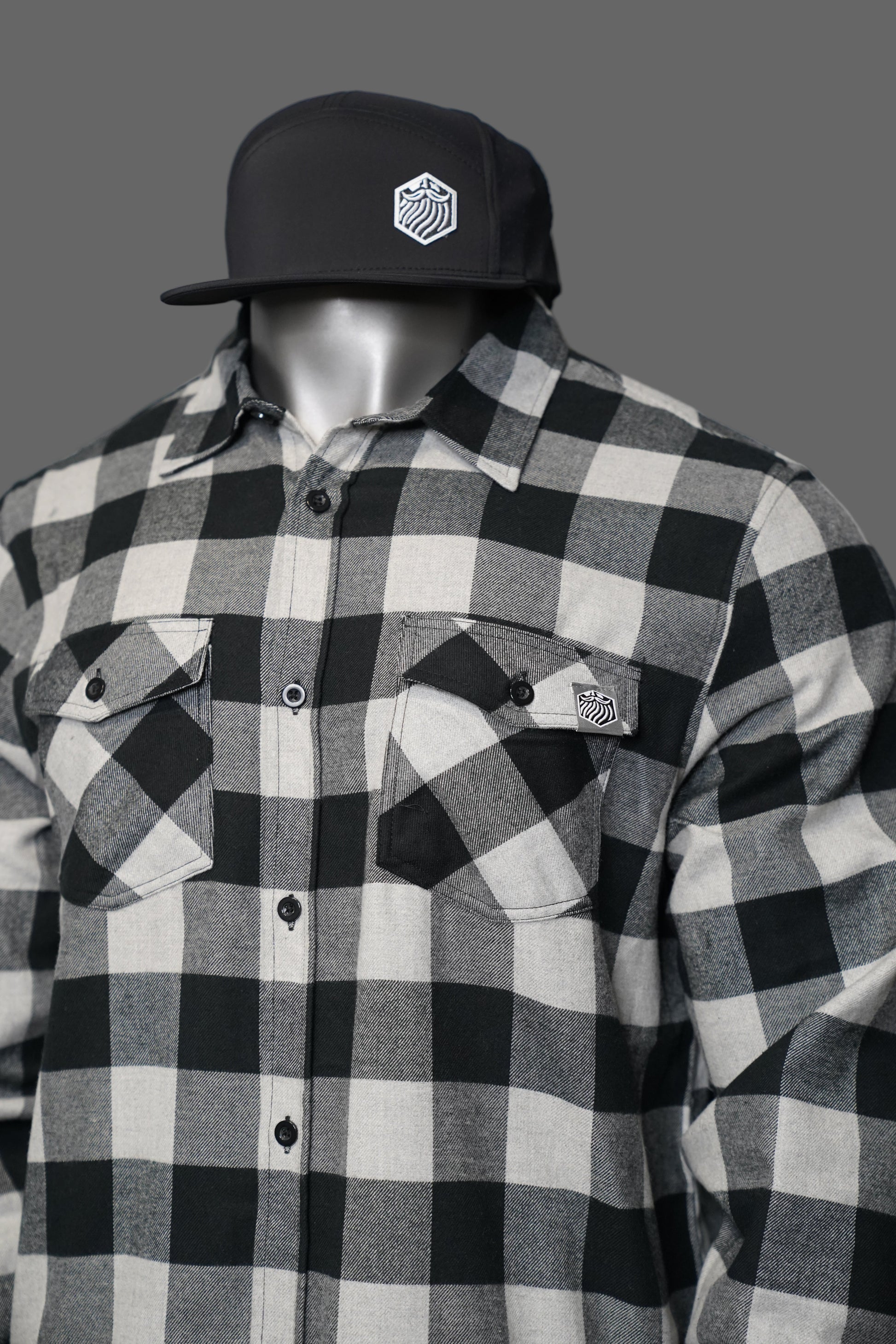 Black and white checkered shirt with a cap and brand on a gray background