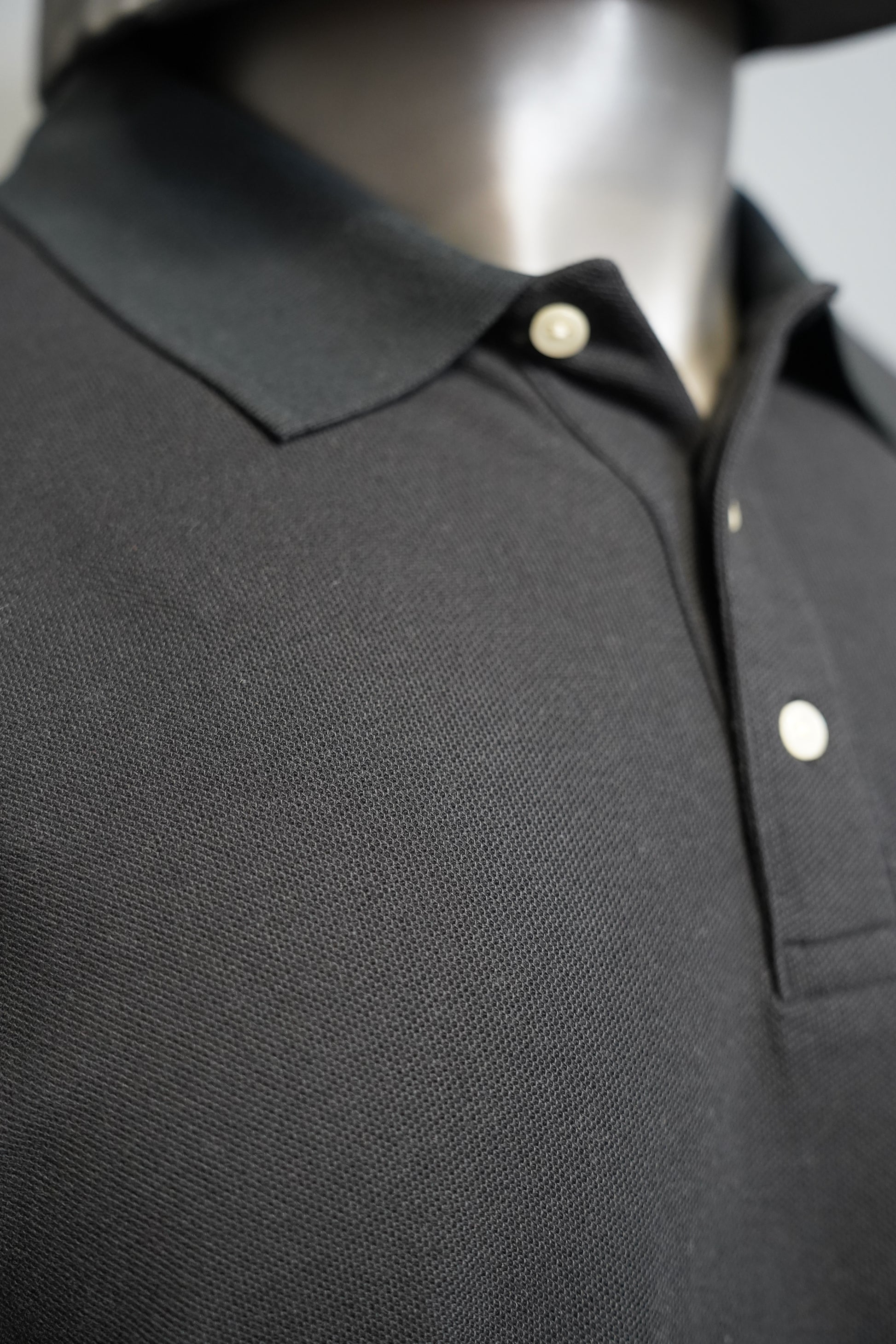 Black polo shirt against a gray background