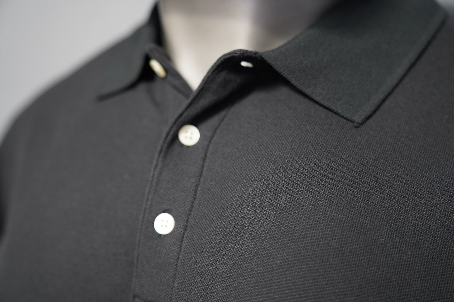 Close-up of a black polo shirt on a gray background
