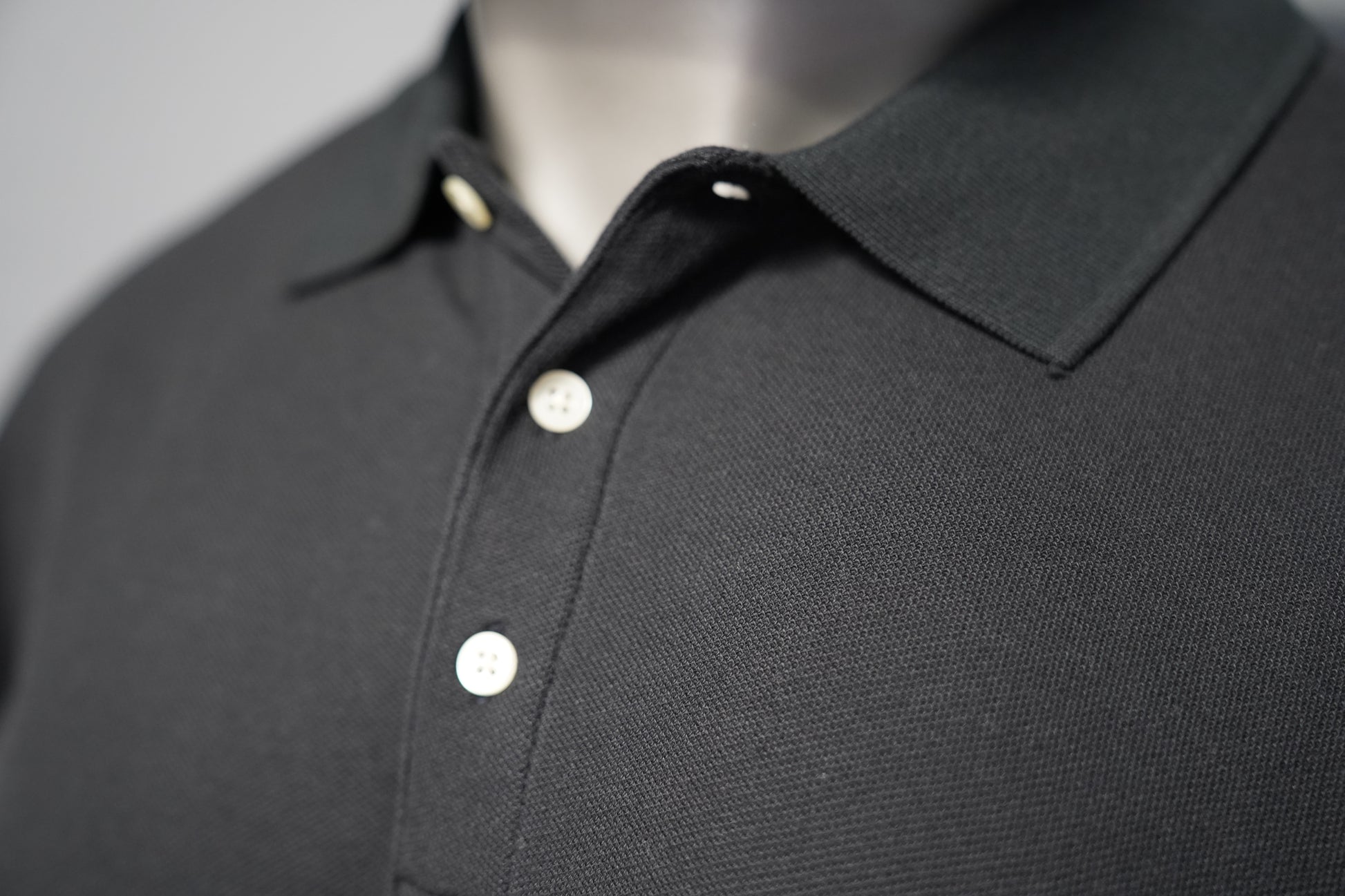 Close-up of a black polo shirt on a gray background