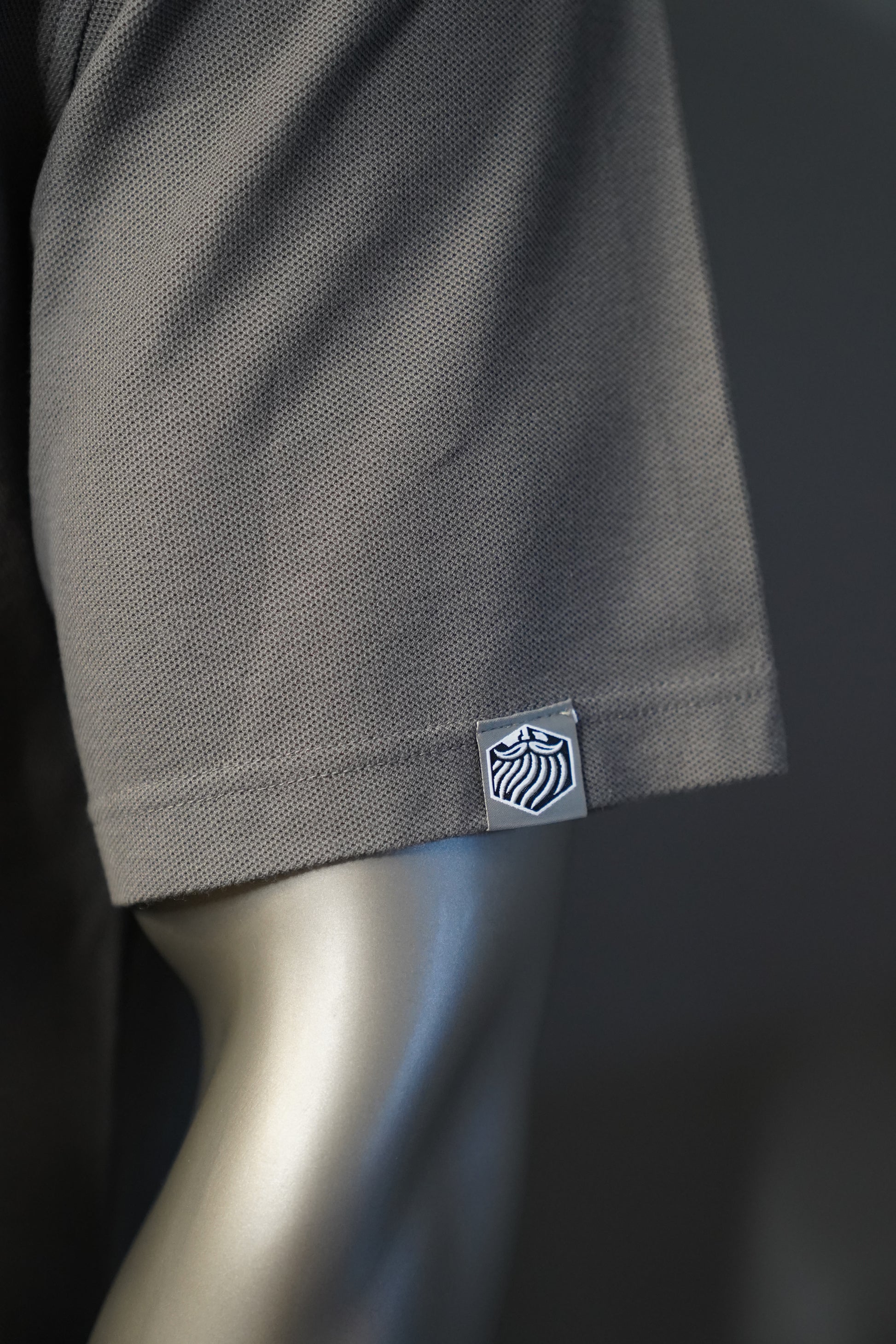 Close-up of a graphite garment with a brand logo on the sleeve.