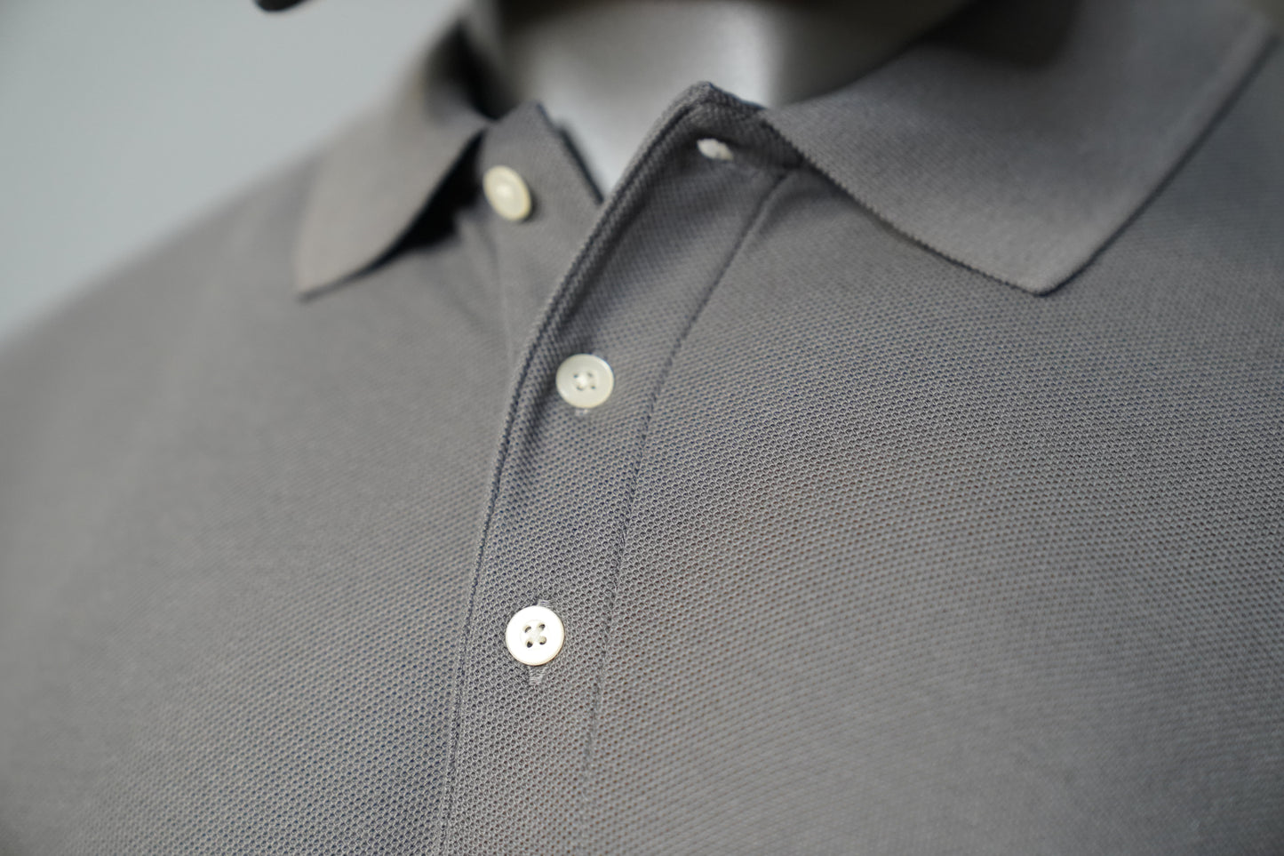 Close-up of a graphite polo shirt with buttons.