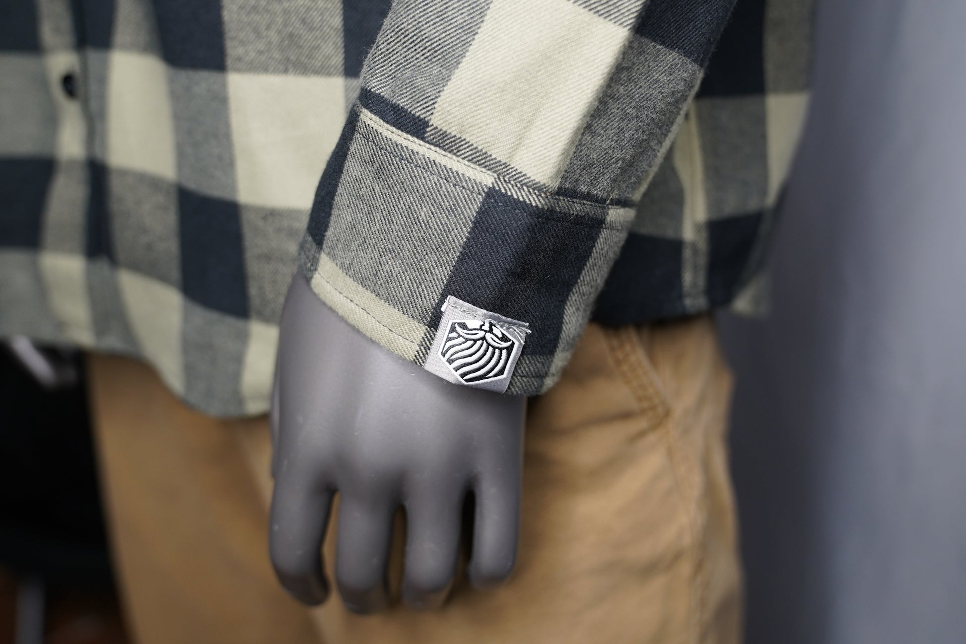 Close-up of black and olive checkered fabric texture sleeve with brand